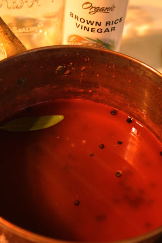 Simmering vinegar, salt, sugar, peppercorns, and a bay leaf